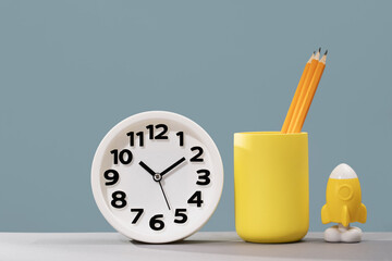 Plain clock and stationery on pastel blue background desk. Ten o'clock. copy space, time management...