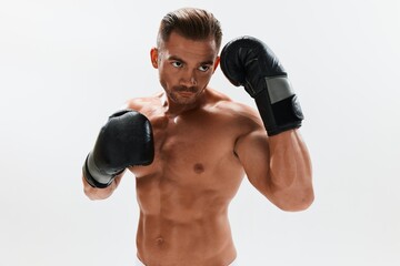 Fototapeta na wymiar Man athletic bodybuilder poses in boxing gloves with nude torso abs in full-length background, boxing and martial arts. Advertising, sports, active lifestyle, competition, challenge concept. 