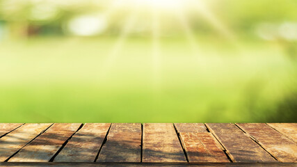 Wooden table top with natural green blurred background or various leaves, fresh bright sunlight, product empty concept.