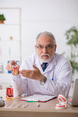 Old male doctor dentist working in the clinic