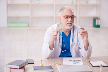 Old male doctor suggesting pills in the clinic