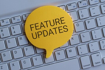 Top view image of keyboard and speech bubble with text FEATURE UPDATES. Technology concept