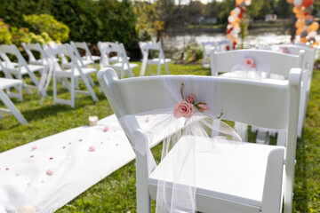 vue du dos d'une chaise pliante blanche décorée pour une cérémonie de mariage extérieur