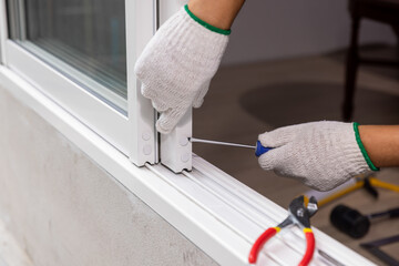 Construction worker repairing the sliding window. Open cap of adjust rail wheel.