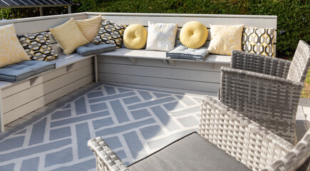 vue sur un espace de jardin avec du mobilier d'extérieur avec coussins gris et jaune
