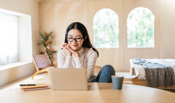Portrait of nerd sme business asian woman wear glasses work from home at online computer desktop table. Asia freelancer girl using laptop in bed room. Small business sme digital network technology.
