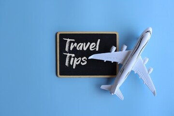 Toy plane and chalkboard with text TRAVEL TIPS. Travel and transportation concept