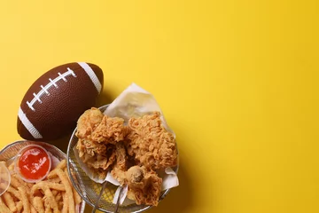 Foto op Aluminium Top view of snacks for watching a football game. Super Bowl or Playoff concept on yellow background with copy space. © Gatot