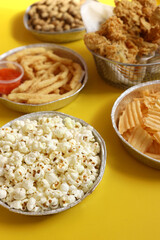 Crackers chips snacks and junk food on yellow background