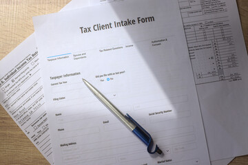 tax forms with calculator and pen on wooden desk