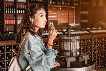 A contented female visitor to a winery pauses to enjoy a sip of a refreshing white wine.