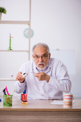 Old male dentist working in the clinic