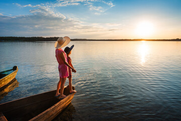 Fototapeta na wymiar Mother and child at sunset in boat on seascape background.