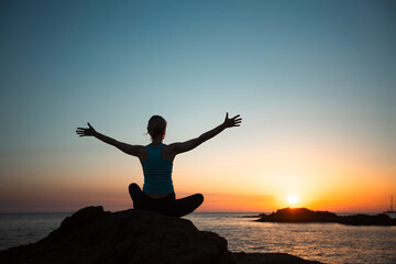 Yoga woman meditating on the rocks of the Atlantic Ocean.
