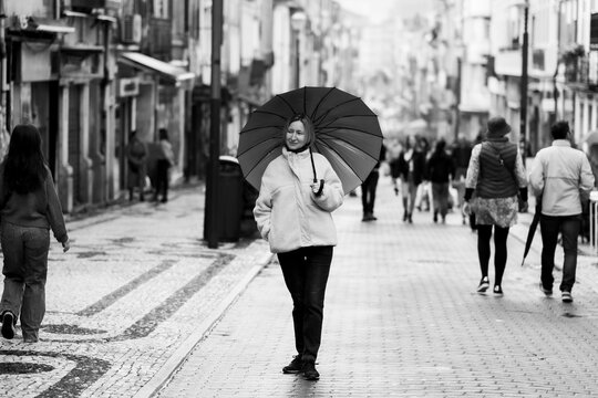 A woman with an umbrella on Santa-Catarina main street in Porto, Portugal. Black and white photo.