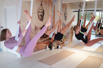 workshop of air yoga and stretching in yoga studio. women practices different inversion antigravity...