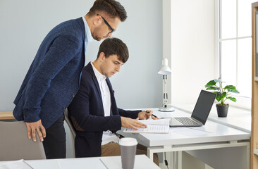 Two male workers find a mistake in a business document while doing paperwork in the office...