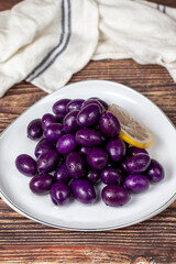 Kalamata olive with blueberries flavor. Purple olives on wood background.