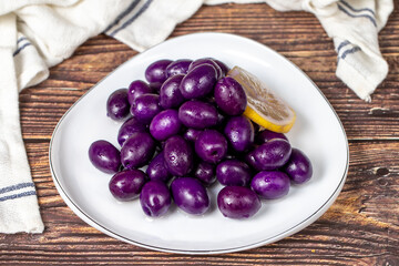 Kalamata olive with blueberries flavor. Purple olives on wood background.