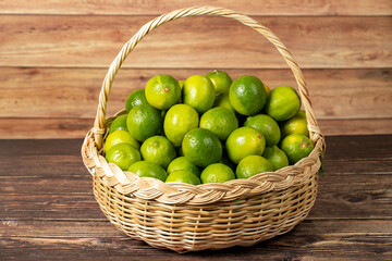 Lime lemon. Pile of lemons in basket on wood background