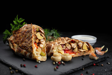 Shawarma with meat, mushrooms, vegetables and sauce, on a black background