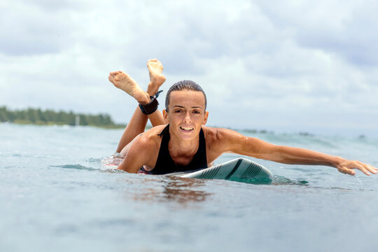 Portrait of woman surfboarding against cloudy sky