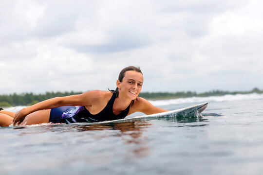 Portrait of woman surfboarding in sea against cloudy sky