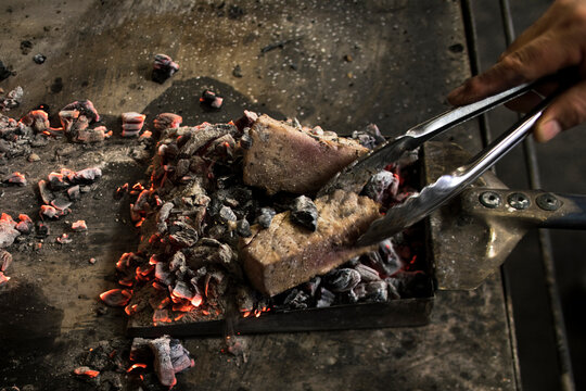 Cropped hand roasting meat on coal