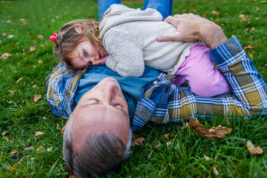 Father and daughter lying on grassy field in park