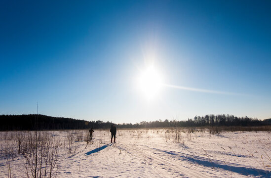 Men skiing on snow covered field against blue sky