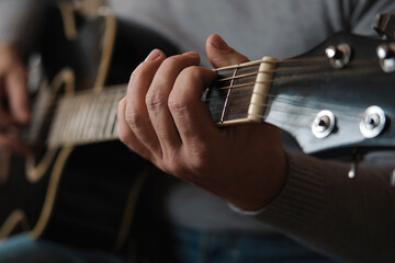 Playing the guitar. Strumming black acoustic guitar. Musician plays music. Man fingers holding...