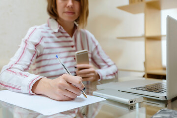 Midsection of businesswoman writing on paper while working at home office