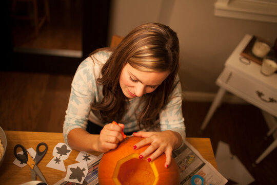 High angle view of woman carving pumpkin while sitting at table during Halloween