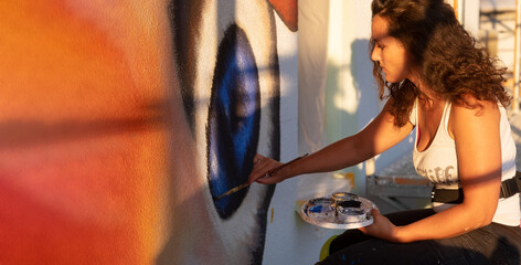 sexy female artist painter woman with curly brunette hair paints a street art peacock butterfly...