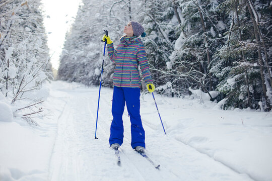 Full length of woman in ski-wear looking up while standing on snow covered field