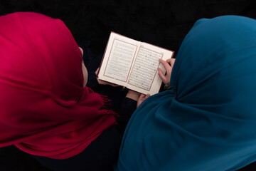 Two Muslim girls reading a holy book Quran inside the mosque.