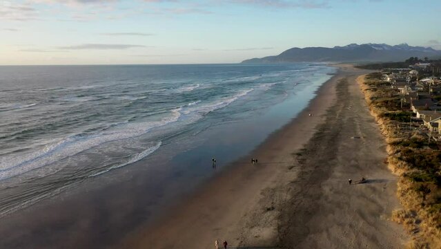 Rockaway Beach with beachgoers, slow aerial flight north