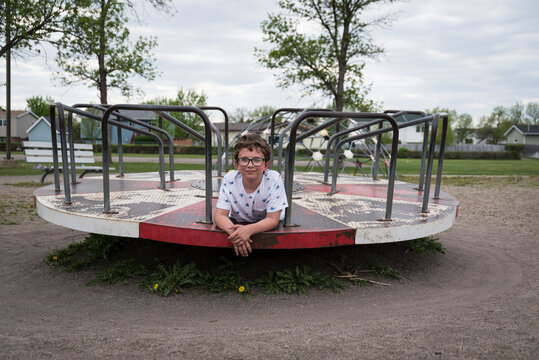 Portrait of boy lying on merry-go-round at playground