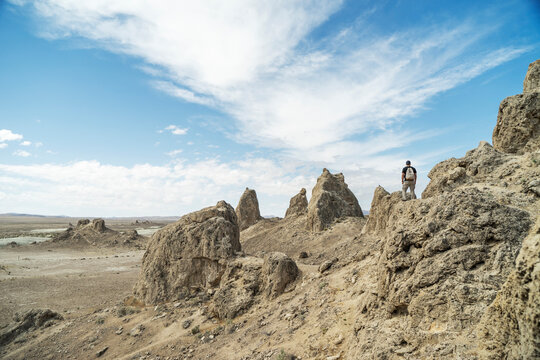 Rear view of hiker looking at view while standing on mountain cliff against cloudy sky