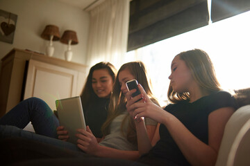 Low angle view of teenage girl looking at friends using tablet computer