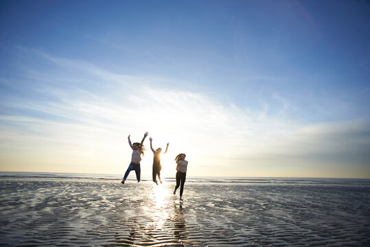 Female friends enjoying at beach against sky