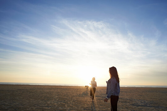 Female friends playing at beach against sky