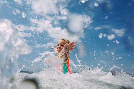 Girl playing in sea against cloudy sky
