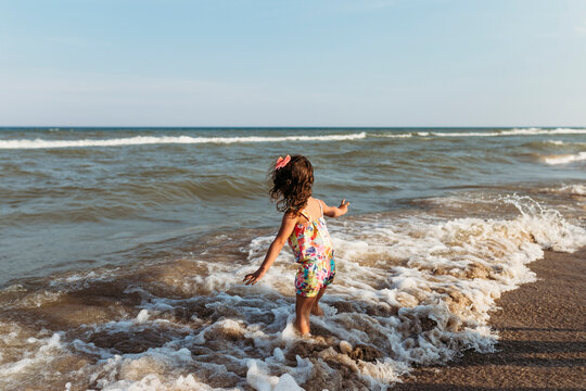 Carefree girl playing in waves at beach against clear sky