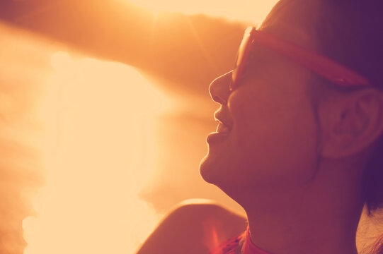Close-up of happy woman wearing sunglasses while looking away at beach