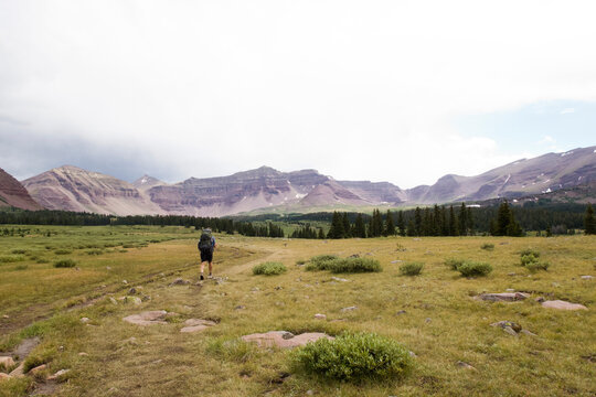 Rear view of hiker with backpack at Henry's Fork Trail against mountain ranges and sky