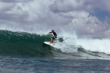 Carefree man surfing on sea against cloudy sky