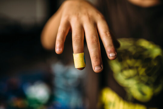 Cropped image of boy showing bandage on finger at home