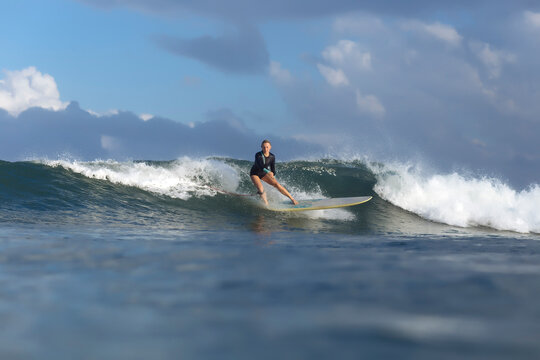Carefree woman surfing on sea against cloudy sky