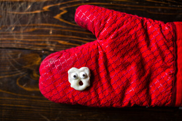 Overhead view of anthropomorphic cookie on oven mitt at wooden table